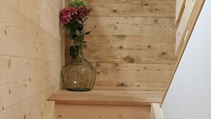 Eine Holztreppe mit einer klaren Glasvase, gefüllt mit rosa Blumen, auf der Zwischenebene.