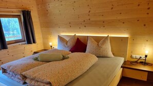 Ein Schlafzimmer einer Holzhütte mit einem Bett, Kissen und Nachttischlampen.