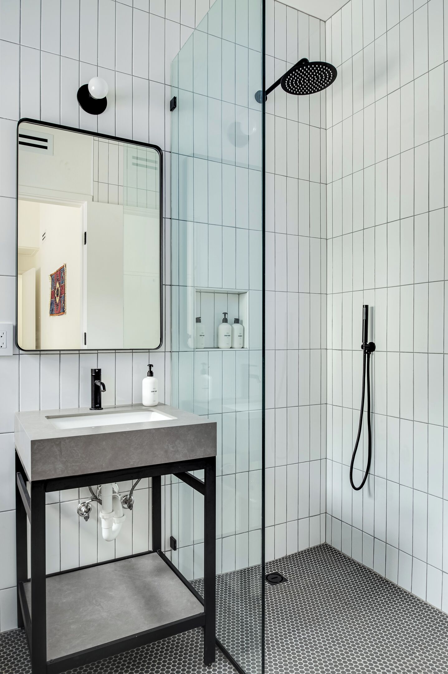 A modern bathroom with a glass shower enclosure, a sink with a mirror, and a tiled floor.