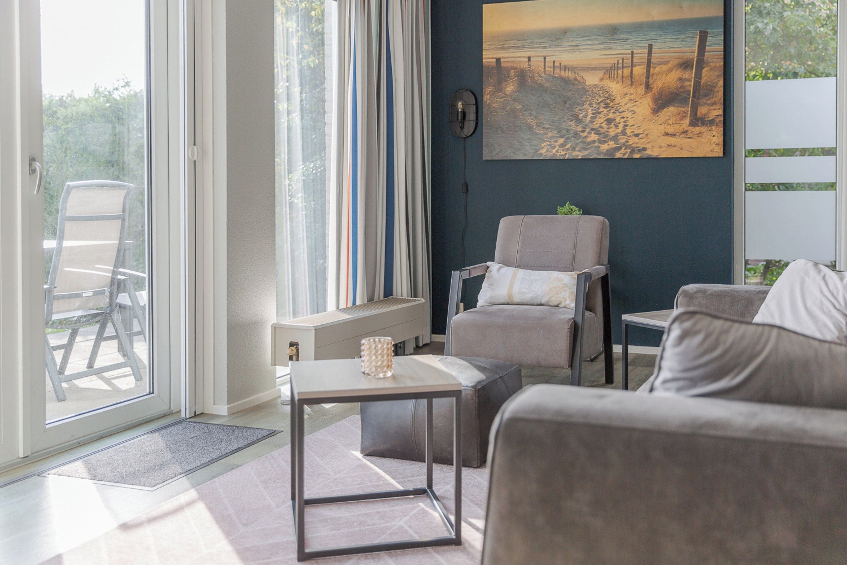 A modern living room with a sofa, a chair, a small table, and a painting on the wall.