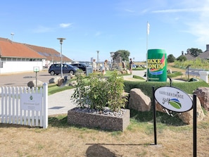Entrada a un campo de golf con un letrero que dice 'Adventure Golf', un gran anuncio de 'Faxen Konni' y un letrero de 'Karrebaeksminde'.