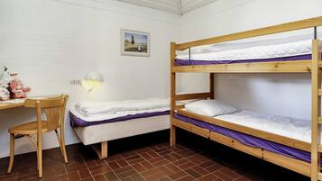 A bunk bed room with a desk and chair, a wall-mounted lamp, and a small picture.