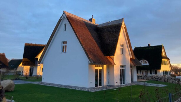 A modern house with a steeply pitched roof, white exterior walls, and a well-maintained lawn. - Small Boulder Comfortable Vacation Home (Rerik)