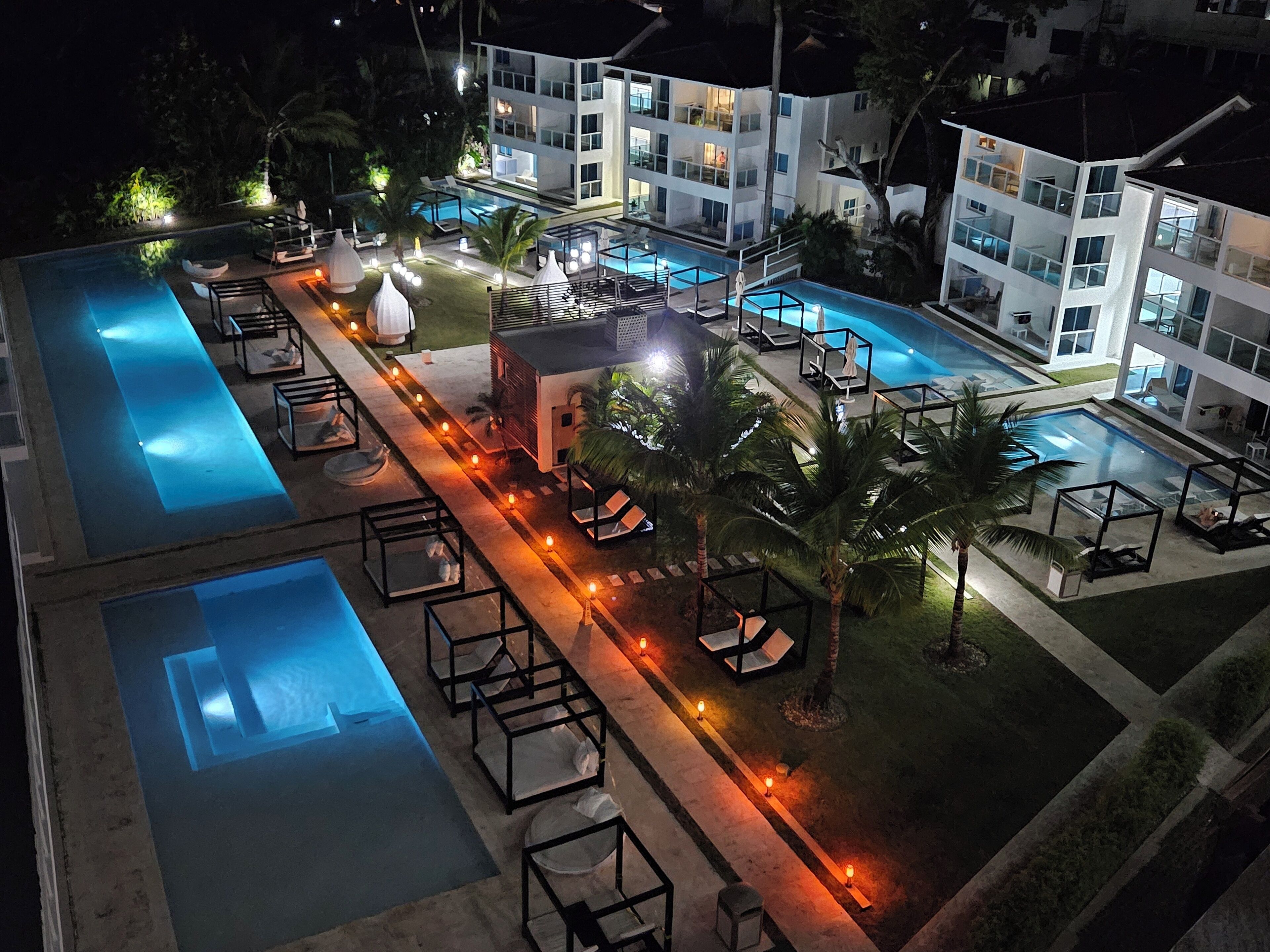 Un complexe hôtelier doté de plusieurs piscines, d’espaces de détente et d’un espace extérieur bien éclairé.