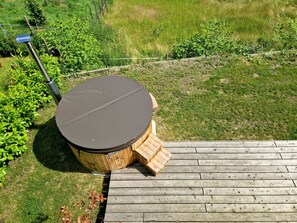A round wooden table with a black top, surrounded by a wooden deck.