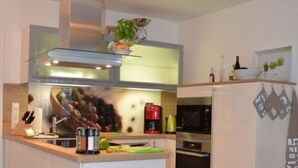 A modern kitchen with a central island, stainless steel appliances, and a tiled backsplash. - Siam Comfortable Holiday Residence (Borkum)