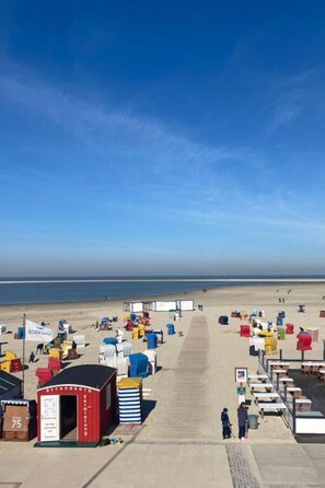 A beachside area with a long pathway leading to beach huts and a small building with signage. - Siam Comfortable Holiday Residence (Borkum)