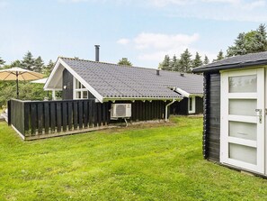 Une maison avec un jardin clôturé, un patio couvert et une cheminée.