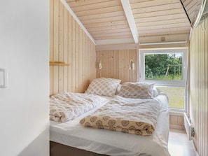 A bedroom with a bed, wooden walls, a window, and a view of greenery outside. - 7 Person Holiday Home in Jerup (Jerup)