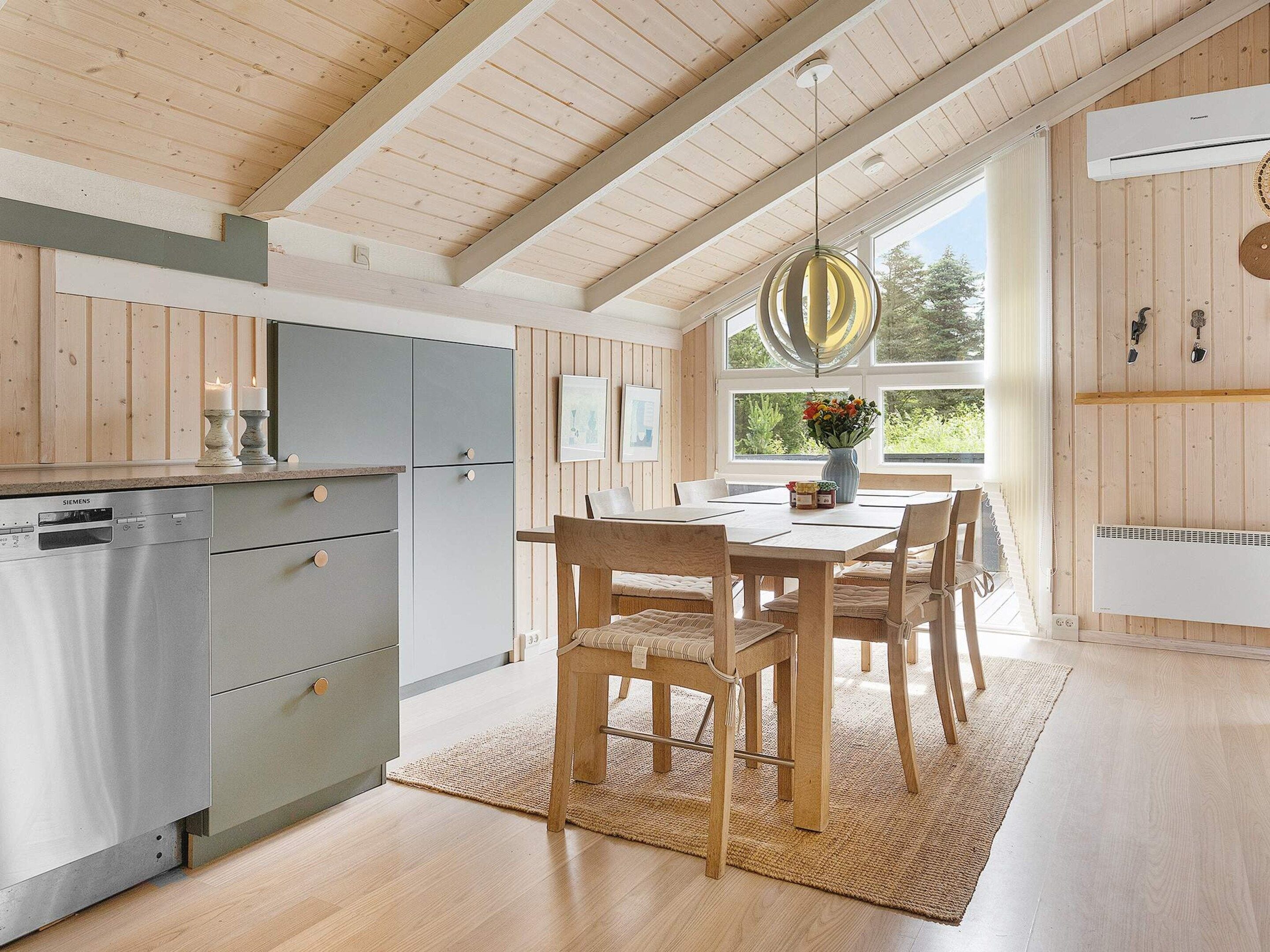 Una cucina moderna con lavastoviglie integrata, mobili in legno e zona pranzo con tavolo e sedie.