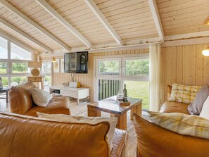 A cozy living room with leather sofas, a wooden coffee table, and a TV mounted on the wall. - 7 Person Holiday Home in Jerup (Jerup)