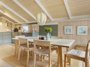 Une cuisine moderne avec des meubles en bois, un coin repas comprenant une table et des chaises, et un luminaire suspendu.