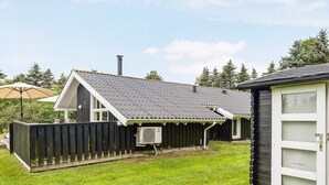 Une maison avec un jardin clôturé, une cheminée et une véranda couverte.