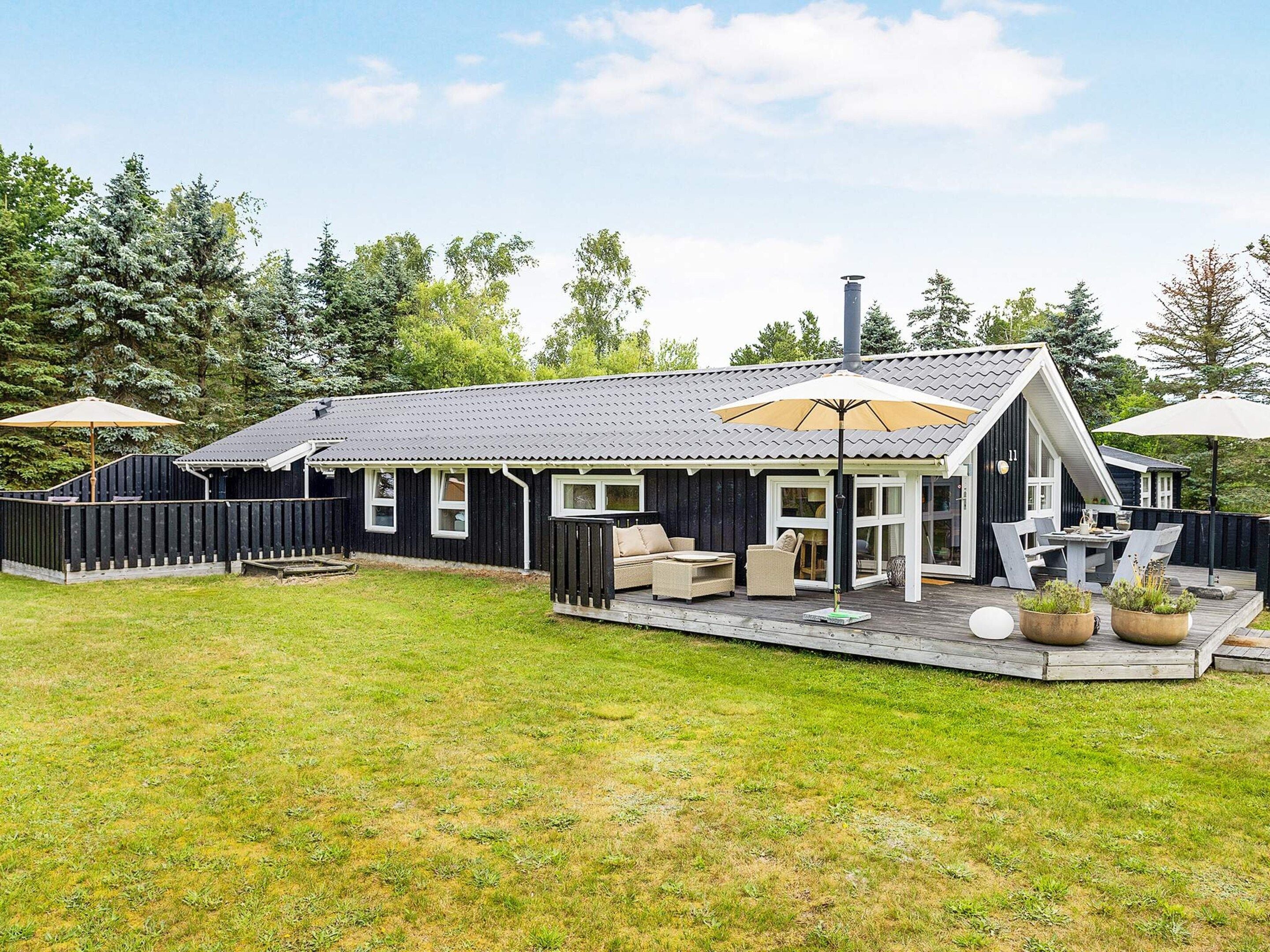 A modern house with a deck, outdoor seating, and a chimney.
