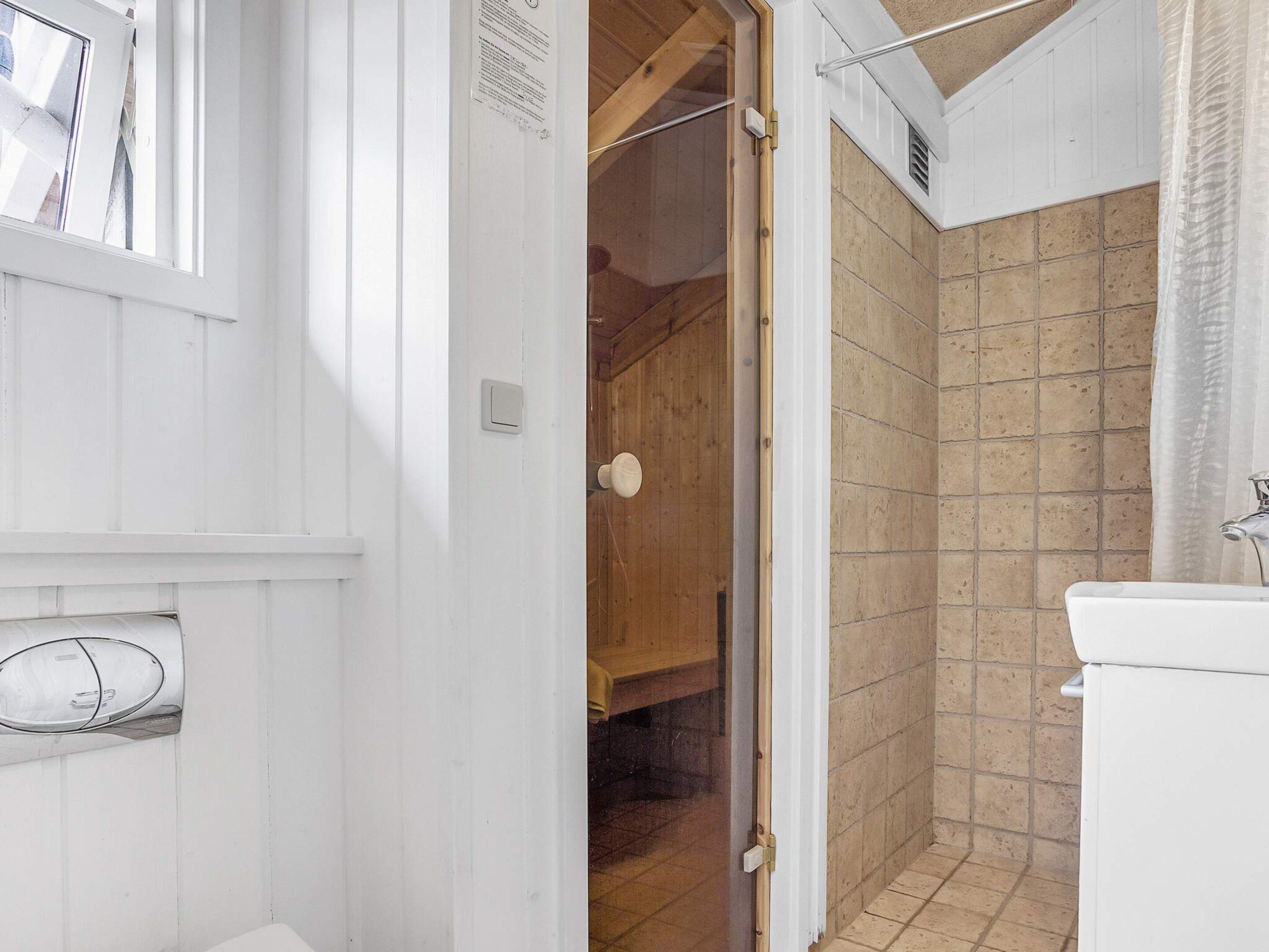 Une salle de bain avec une douche, des toilettes et une fenêtre.