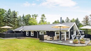 A modern house with a patio, outdoor furniture, and a large umbrella. - 7 Person Holiday Home in Jerup (Jerup)