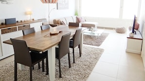 A modern living room with a dining area, a sofa, a coffee table, and a TV. - Apartment in Nieuwpoort by the Beach (Nieuwpoort)