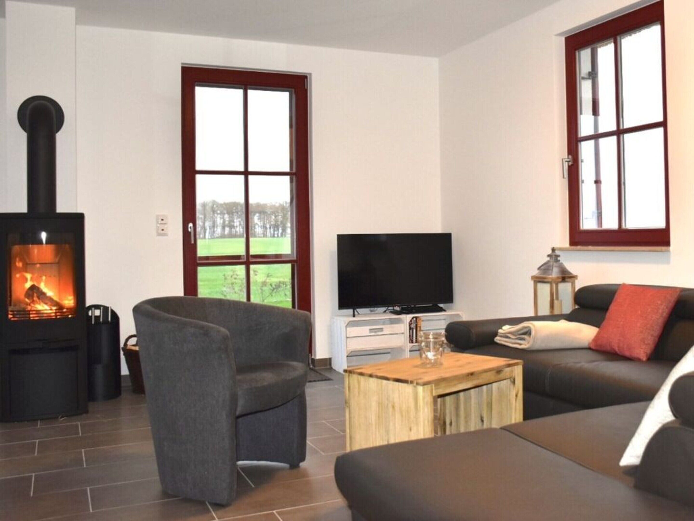 A living room with a fireplace, a sofa, a television, and a window with a view of a green landscape.