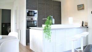 A modern kitchen with built-in appliances, a central island, and a hanging plant. - Chalet in Zeeland by the Lake (Wemeldinge)