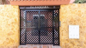A building entrance with a stone wall, a black gate, and a sign reading "Ed. SAQQARA". - Spacious Apartment With 2 Terraces (Motril)