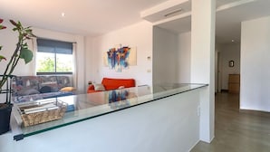 A modern living room with a glass-top coffee table, a red sofa, and abstract art on the wall. - Spacious Apartment With 2 Terraces (Motril)
