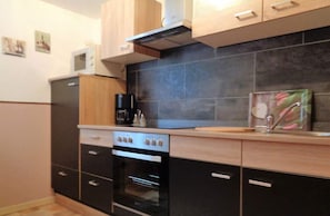 Eine kleine Küche mit Herd, Backofen und Kaffeemaschine auf der Arbeitsfläche.