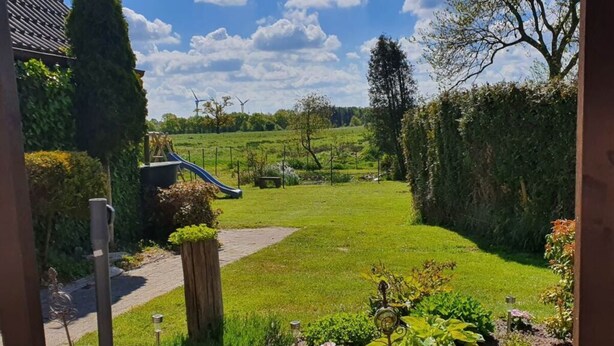 A garden with a lawn, a wooden path, and a small pond with decorative stones.