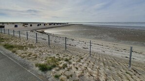 A beach with a fence, a row of colorful containers, and a clear sky.