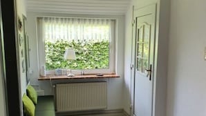 A narrow hallway with a bench, a radiator, and a door.