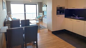 A modern apartment with a dining area, kitchen, and a balcony with a view. - Apartment in Nieuwpoort Near Sandy Beaches (Nieuwpoort)