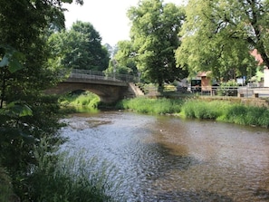 A stone bridge over a calm river, surrounded by lush greenery and trees. - Lovely Apartment in Himmelkron (Himmelkron)