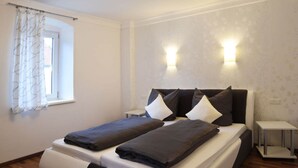 A modern bedroom with a bed, two bedside tables, a window with curtains, and wall-mounted lighting. - Lovely Apartment in Himmelkron (Himmelkron)