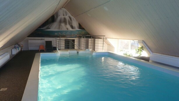 An indoor swimming pool with a sloped ceiling and a waterfall feature. - Lovely Apartment in Himmelkron (Himmelkron)