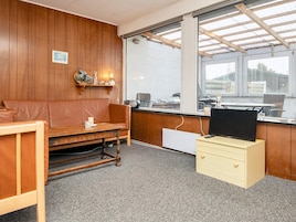 Una habitación con pared de madera, un sofá, un escritorio con computadora y una ventana con vista al exterior.