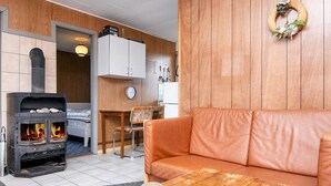 Una sala de estar acogedora con un sofá de cuero, una mesa de madera con una vela y un estufa de leña.
