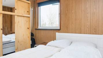 Ein Schlafzimmer mit einem Bett, einem Fenster und Holzvertäfelung.