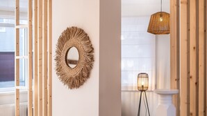 A room with a wooden slat wall, a woven mirror, and a floor lamp. - Garden Villa Steps From Beaches (Koksijde)