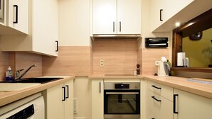 A modern kitchen with white cabinets, a built-in oven, and a sink. - Blomme 0202 Exclusive Apartment With sea View (De Haan)