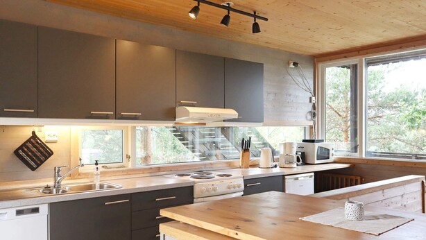 A modern kitchen with grey cabinets, a wooden countertop, and a window providing a view of trees. - 8 Person Holiday Home in Sondeled (Risør)