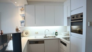Una cocina moderna con armarios blancos, un lavamanos de acero inoxidable y un horno.