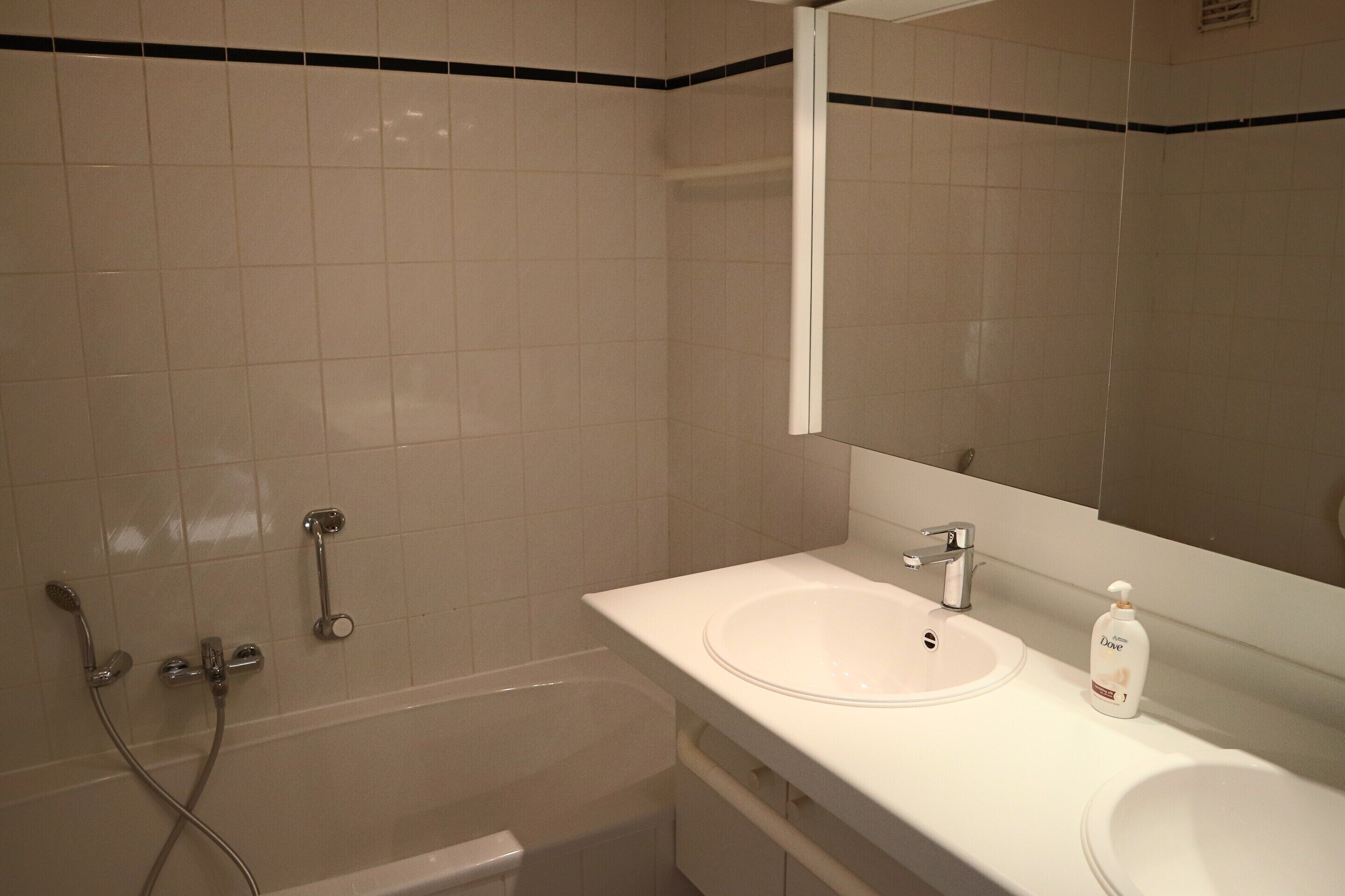A bathroom with a white sink, a mirror, and a shower.