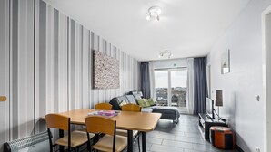 Una habitación de hotel moderna con comedor, sofá y televisor.