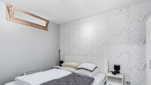 Un dormitorio con cama, mesita de noche, lámpara y pared decorada.
