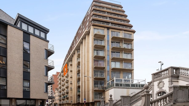 Un edificio de varios pisos con balcones, una escalera y un patio empedrado.