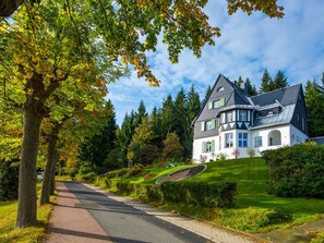 A large, two-story house with a steeply pitched roof, surrounded by lush greenery and trees. - Holiday Apartment Waldfrieden (Altenberg)