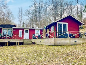A red cabin with a deck and a flag. - 8 Person Holiday Home in Fagerhult (Fagerhult)