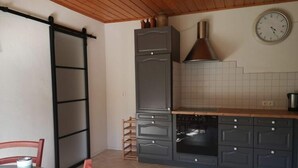 A kitchen with a sliding door, a stove, and a clock on the wall. - Holiday Apartment at the Linden Tree (Dernbach)