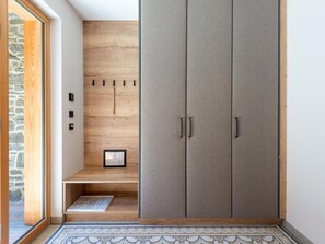A room with a wooden wall, a grey wardrobe, and a small shelf with a framed item.