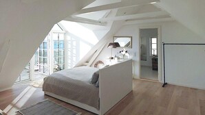 A high-ceilinged attic bedroom with a large skylight, a bed, a desk, and a mirror. - 5 Star Holiday Home in Assens (Assens)