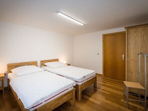 A room with two wooden beds, a wardrobe, and a chair. - Holiday Home Villa Bauer (Traben-Trarbach)
